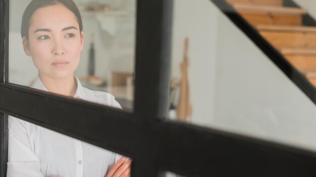 Mujer de ángulo bajo mirando por la ventana