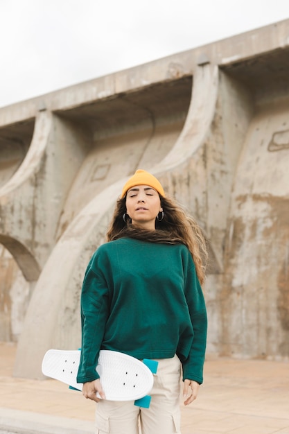 Foto gratuita mujer de ángulo bajo con patineta