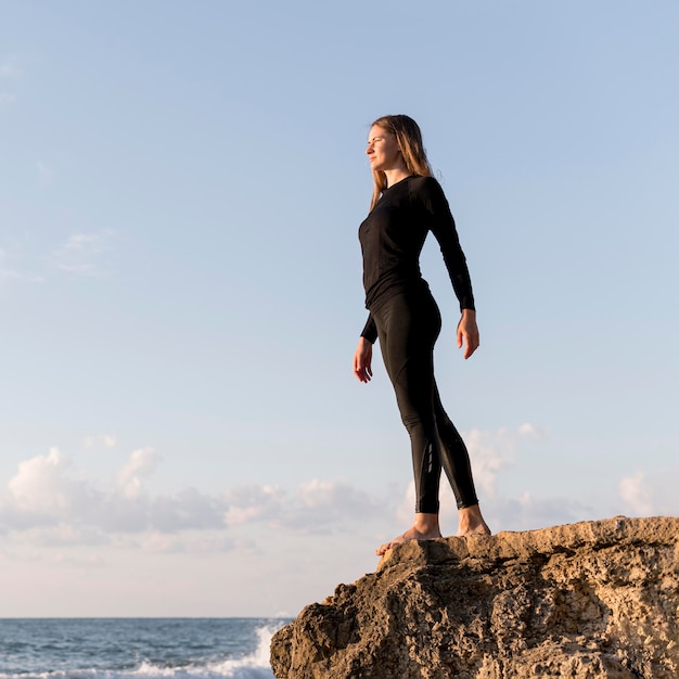 Foto gratuita mujer de ángulo bajo de pie y mirando al mar