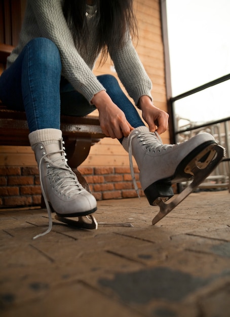 Foto gratuita mujer de ángulo bajo poniéndose patines de hielo