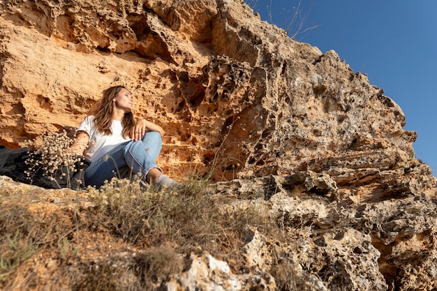 Mujer de ángulo bajo sentada en la costa