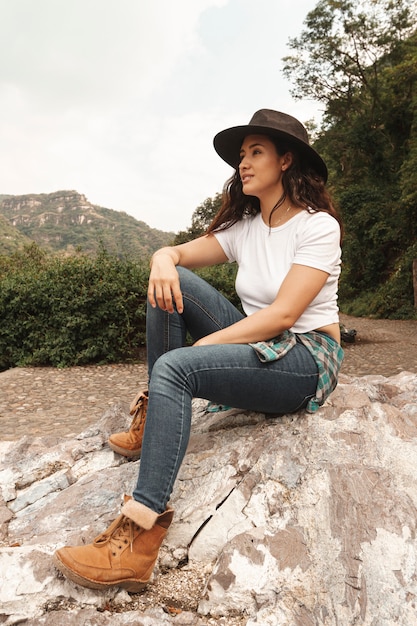 Mujer de ángulo bajo con sombrero en la naturaleza