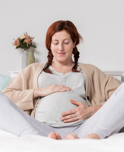 Mujer de ángulo bajo tocando su vientre embarazado
