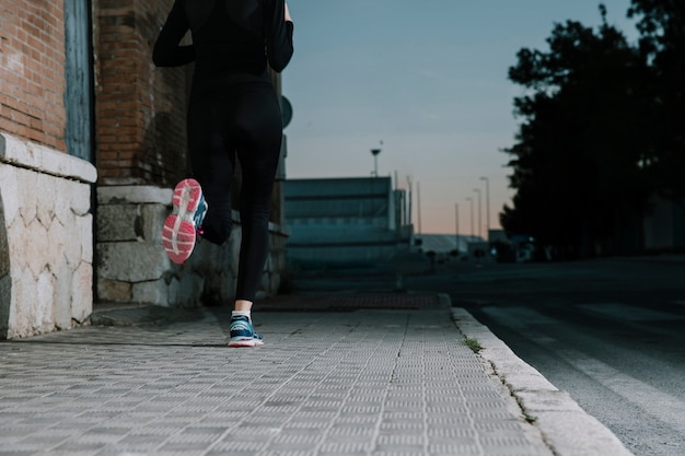 Mujer anónima corriendo en la calle al atardecer