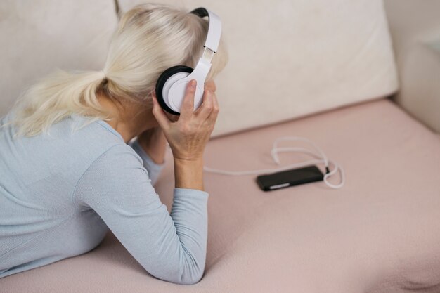 Mujer anónima escuchando música en el sofá