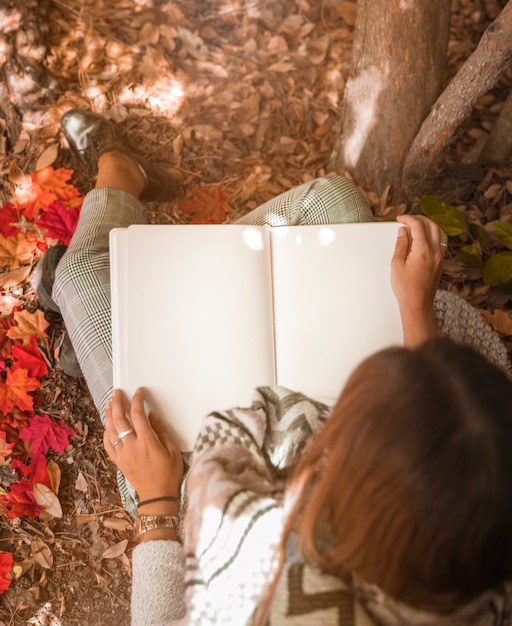 Mujer anónima leyendo en el bosque de otoño