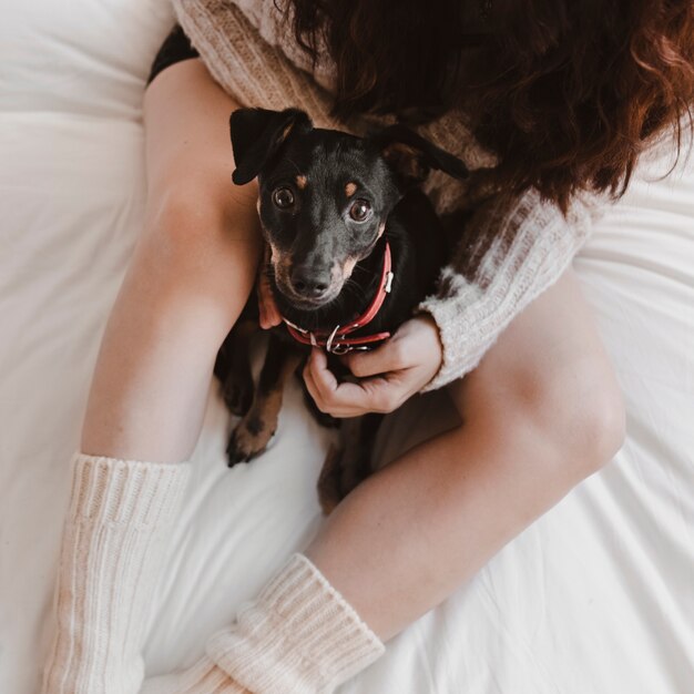 Mujer anónima con perro en la cama