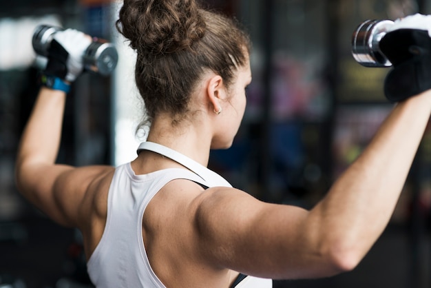 Foto gratuita mujer anónima que ejercita con pesa de gimnasia