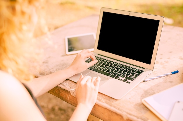 Mujer anónima que trabaja en la computadora portátil en el escritorio afuera