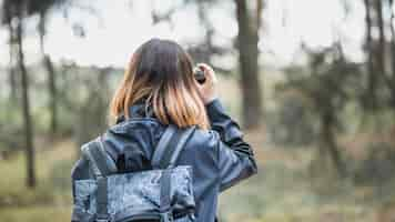 Foto gratuita mujer anónima tomando fotos en el bosque