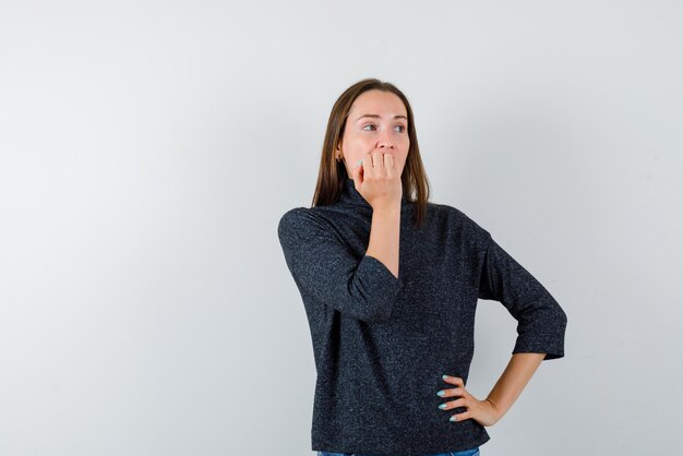 La mujer ansiosa se está mordiendo las uñas en el fondo blanco