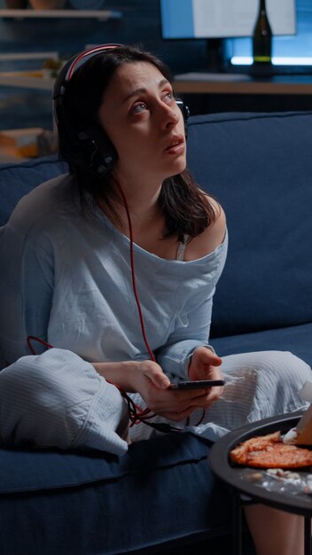 Mujer ansiosa pensativa triste escuchando música usando el teléfono inteligente sintiéndose solo preocupado preocupado por ...