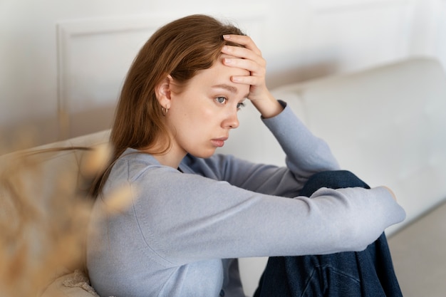 Mujer ansiosa sentada en la vista lateral del sofá