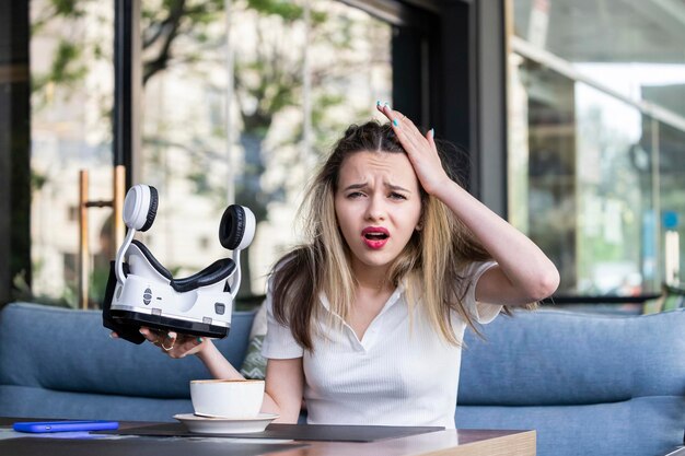 Mujer ansiosa sosteniendo un set de realidad virtual y sintiéndose mal en el restaurante