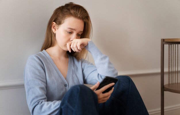 Mujer ansiosa de tiro medio con teléfono inteligente