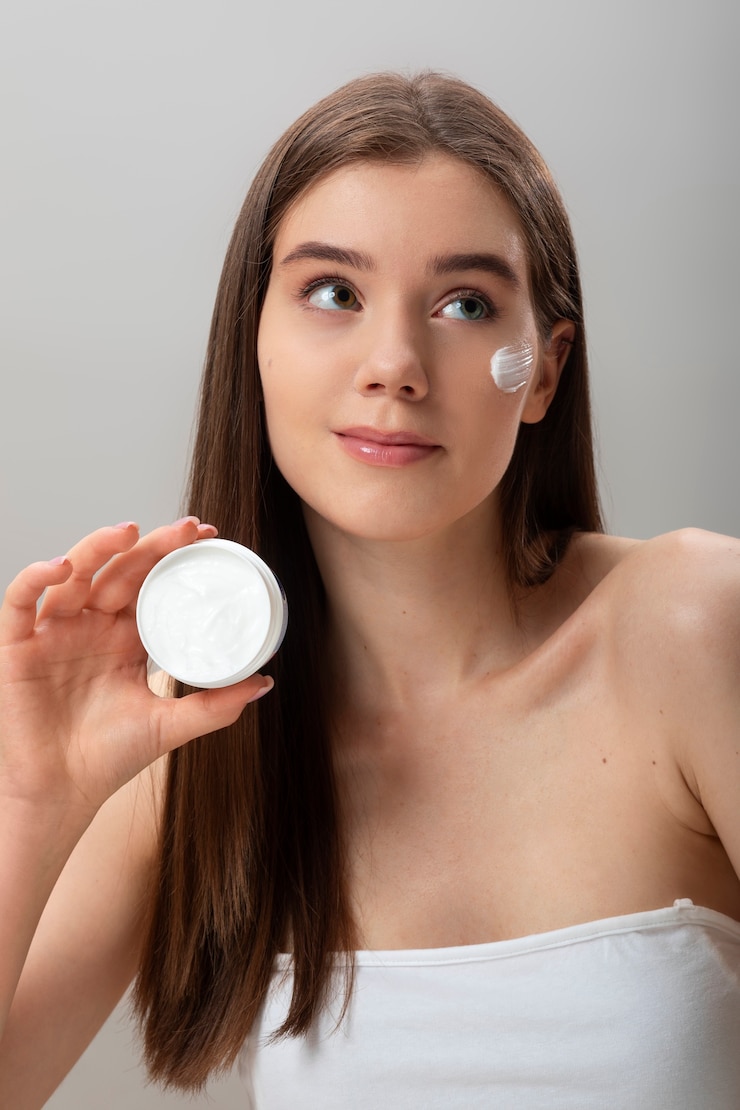 Foto gratuito mujer aplicando crema facial tiro medio