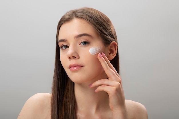 Mujer aplicando crema facial vista frontal