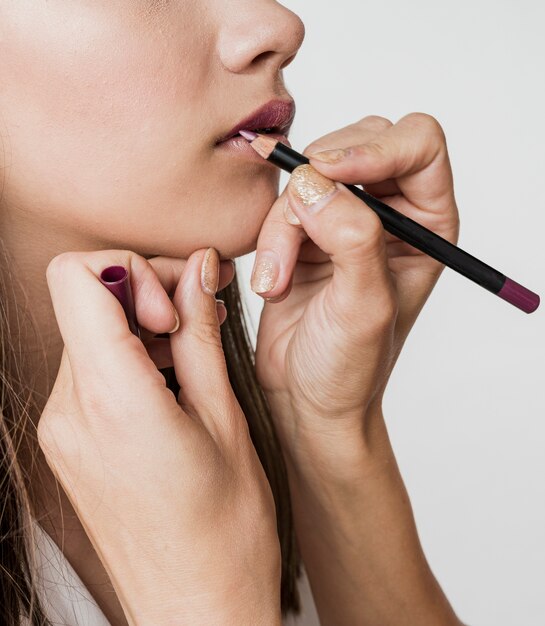 Mujer aplicando delineador de labios en modelo