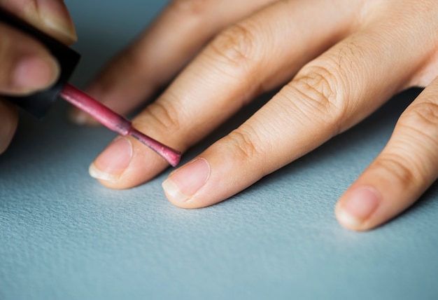 Mujer aplicando esmalte de uñas en las uñas