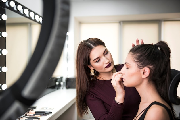 Mujer aplicando maquillaje en modelo