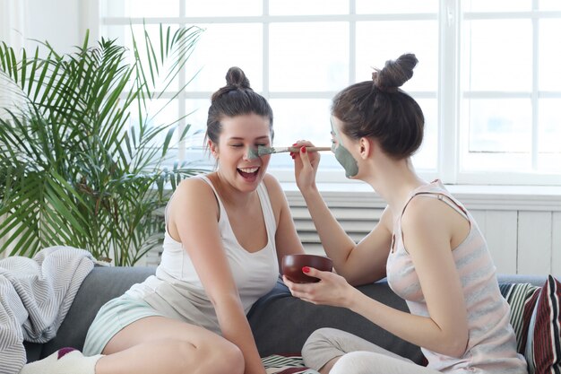 Mujer aplicando una máscara facial a su amiga