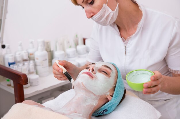 Mujer aplicando una mascarilla facial a una clienta