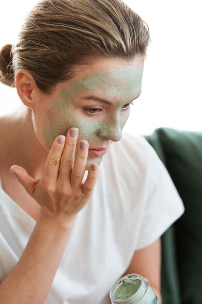 Mujer aplicando mascarilla facial orgánica