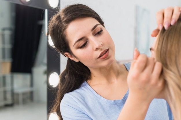 Mujer aplicando pincel delineador de ojos haciendo maquillaje de ojos