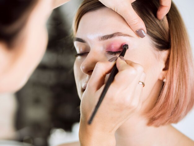 Mujer aplicando sombra de ojos al cliente