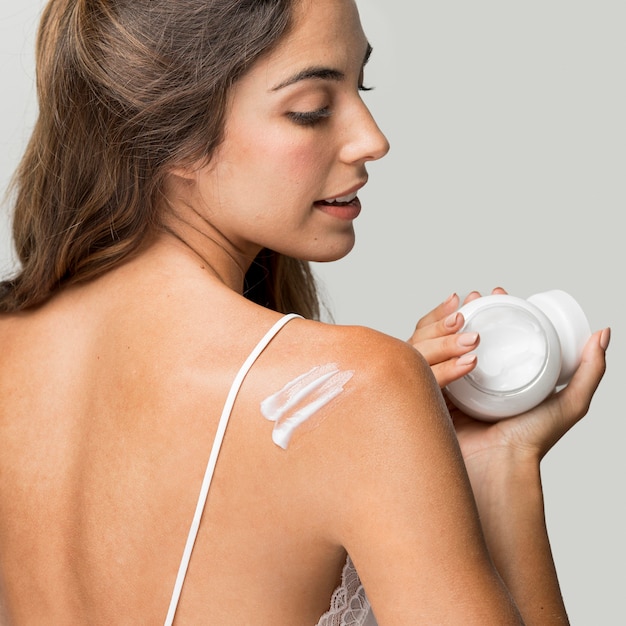 Foto gratuita mujer aplicar crema en la espalda