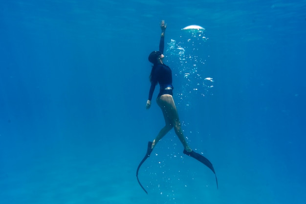 Mujer apnea con aletas bajo el agua