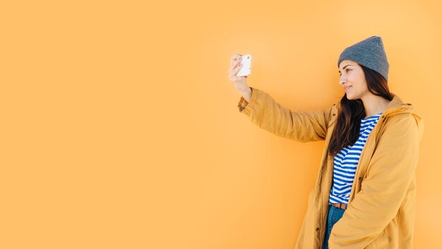 mujer apoyada en la superficie tomando selfie en celular