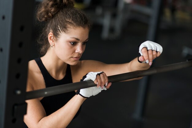 Mujer apoyándose en la barra en el gimnasio