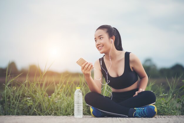 Mujer de la aptitud en auriculares escuchando música durante su entrenamiento y ejercicio en el parque