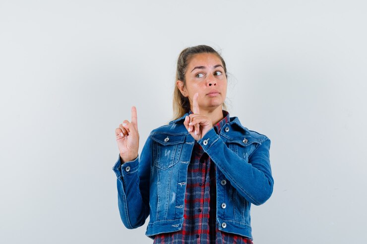 Foto gratuito mujer apuntando hacia arriba mientras mira a un lado en camisa, vista frontal de la chaqueta.