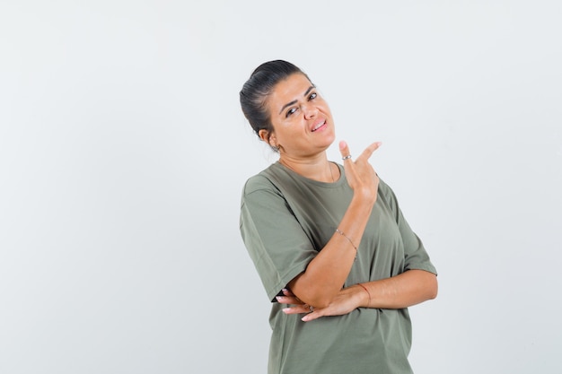 Mujer apuntando a un lado en camiseta y mirando confiada