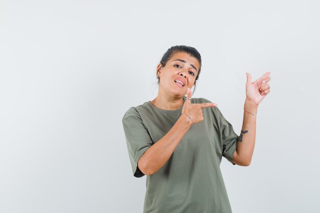 Mujer apuntando hacia un lado en camiseta y mirando confiada