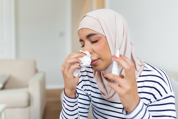 Mujer árabe enferma con hiyab está usando aerosol nasal debido a problemas con la nariz y la respiración