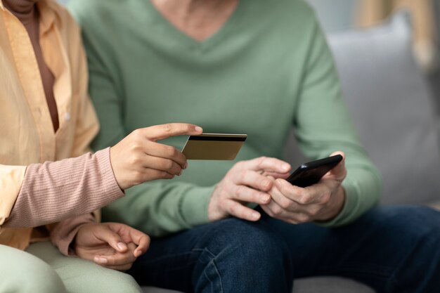 Mujer árabe enseñando a un anciano a usar pago móvil con tarjeta de crédito