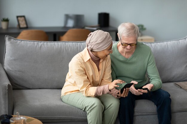 Mujer árabe enseñando a un anciano a usar un reloj inteligente con un teléfono inteligente