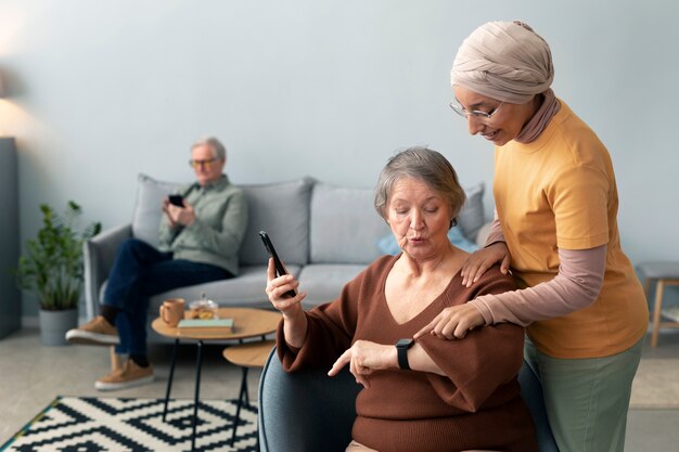 La mujer árabe le está enseñando a la mujer mayor a usar un teléfono inteligente y un reloj inteligente