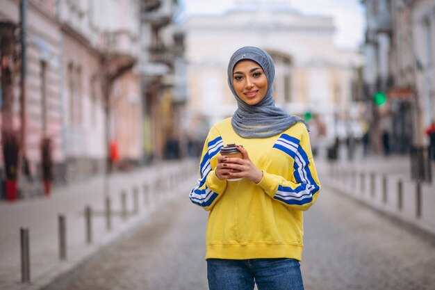 Mujer árabe en hijab ouside en la calle tomando café