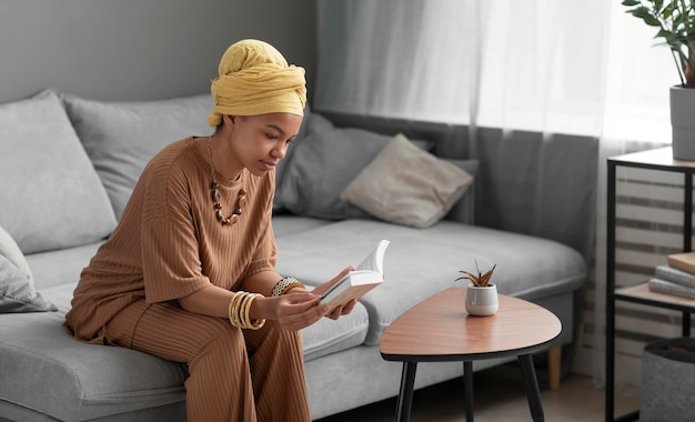 Foto gratuita mujer árabe relajada leyendo un libro en casa