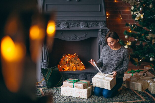 Mujer por árbol de navidad desempaquetar regalos