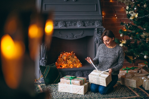 Mujer por árbol de navidad desempaquetar regalos