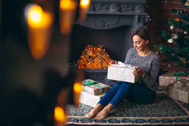 Mujer por árbol de navidad desempaquetar regalos