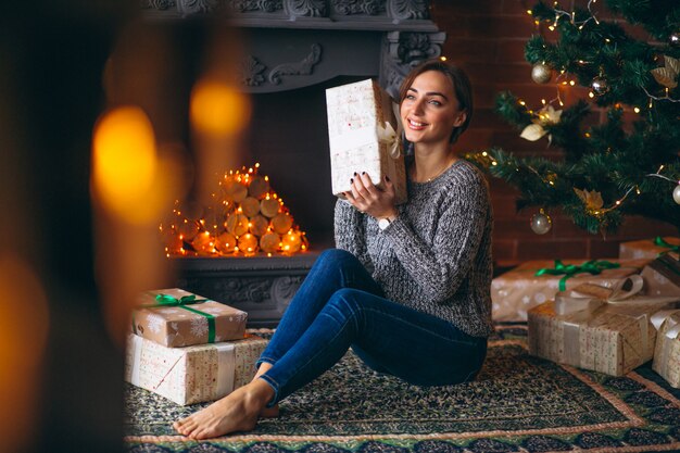 Mujer por árbol de navidad desempaquetar regalos