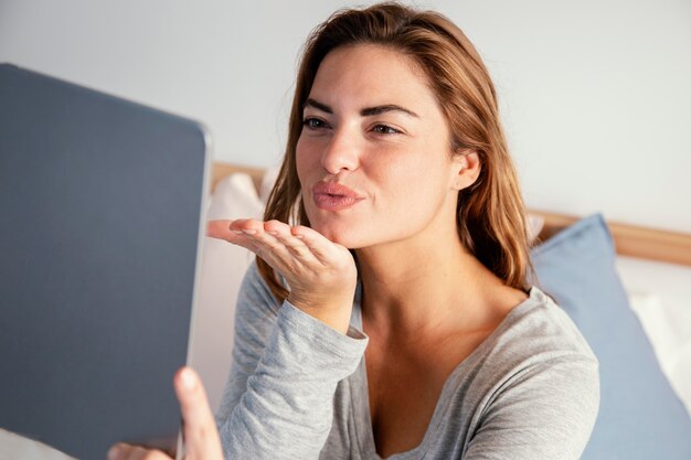 Mujer arco beso hacia videollamada en tableta