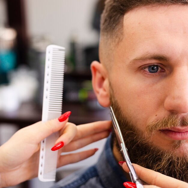 Mujer arreglando la barba de un cliente