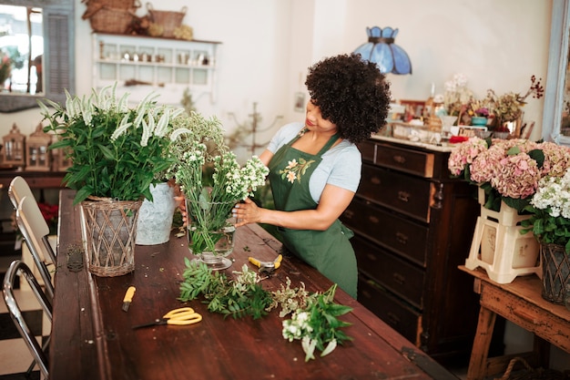 Foto gratuita mujer arreglando flores en la mesa de madera